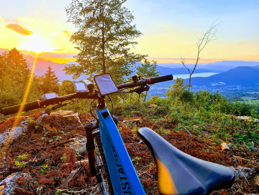 Cycliste consultant un smartphone et un GPS vélo côte à côte avant une sortie, illustrant le choix entre deux options de navigation.