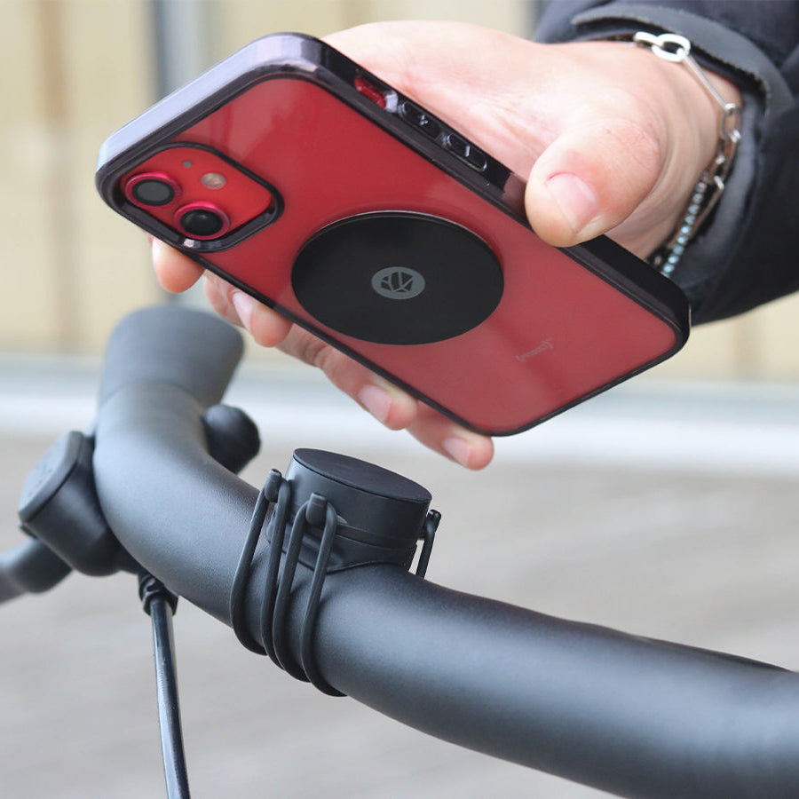 Magnetic attachment of the phone with metal plate on the bike handlebar mount secured with elastic straps