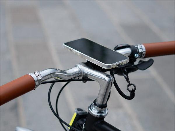 Smartphone fixé magnétiquement au support guidon, démontrant une installation minimaliste. Utilisation du cordon pour encore plus de sécurité