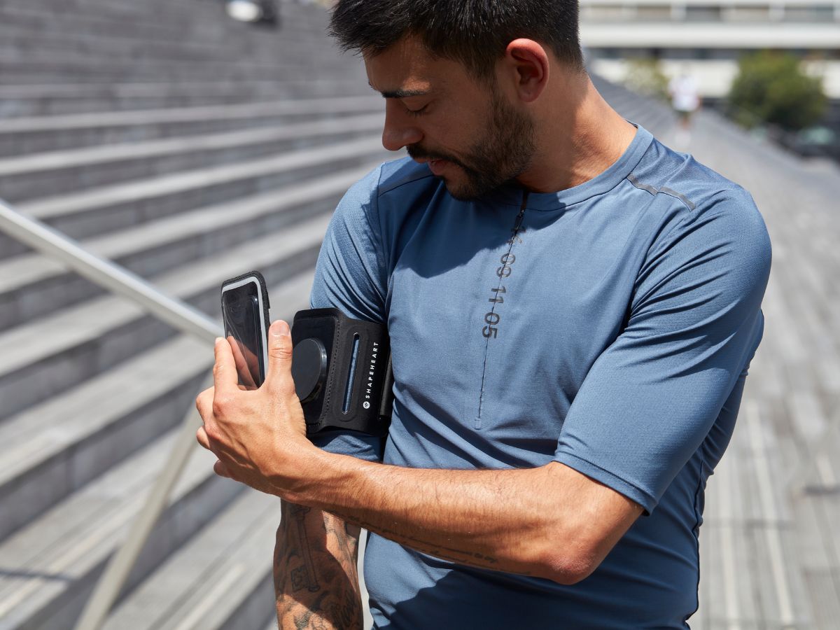 Coureur dans un paysage venteux en tenue ajustée, brassard bien fixé au bras, montrant la stabilité nécessaire pour courir face au vent.