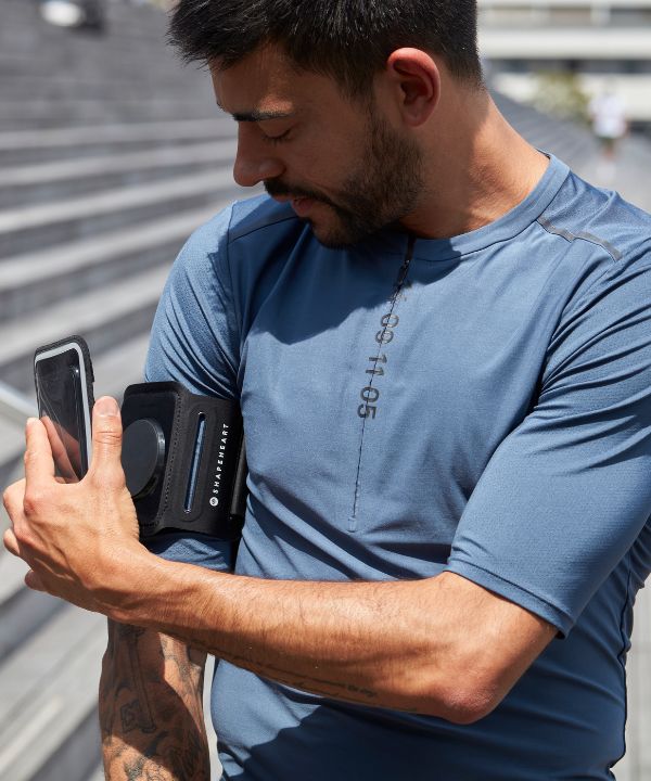 Coureur dans un paysage venteux en tenue ajustée, brassard bien fixé au bras, montrant la stabilité nécessaire pour courir face au vent.