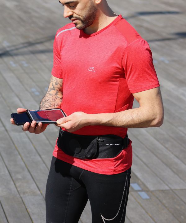 Joggeur en veste imperméable courant sous la pluie avec un brassard étanche visible sur le bras, illustrant la protection des objets électroniques en course.