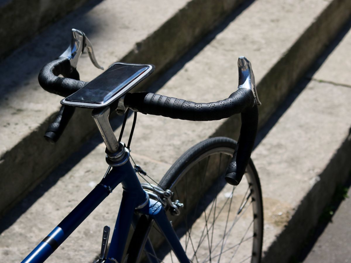 Support smartphone magnétique fixé sur le guidon d’un vélo de route, affichant une appli GPS en action.