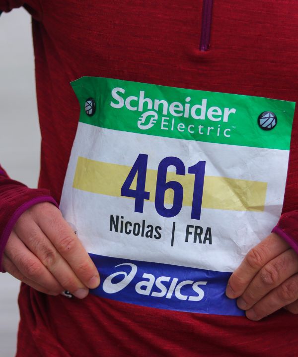 Coureur en action avec dossard bien centré et lisible sur le haut du ventre.