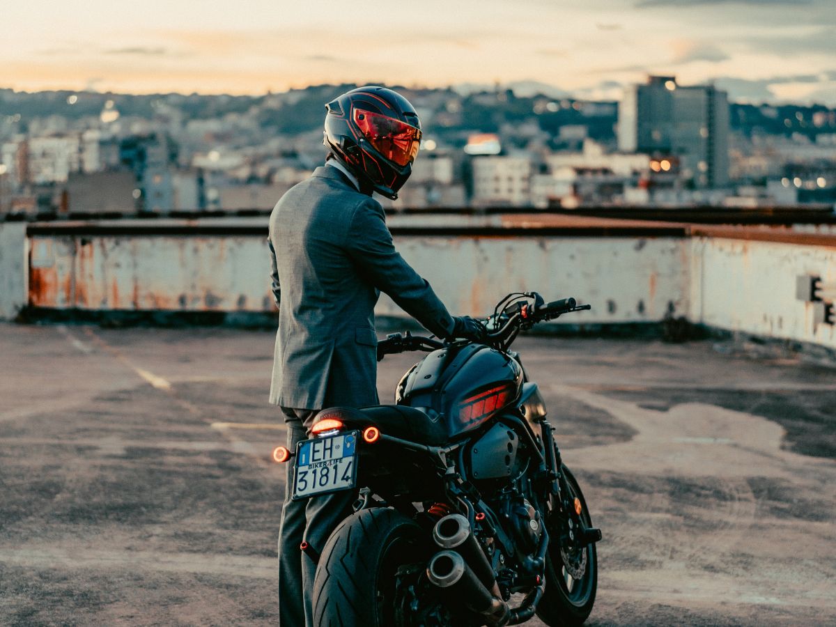 Motard descendant de sa moto et rangeant ses affaires rapidement à l’arrivée.