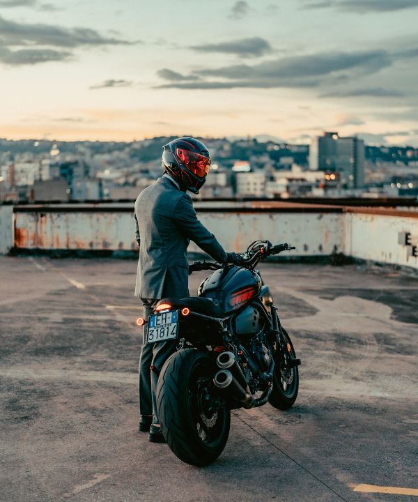 Motard descendant de sa moto et rangeant ses affaires rapidement à l’arrivée.