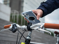 Smartphone équipé d'une plaque métal Shapeheart, fixation clap sur un guidon de vélo urbain.